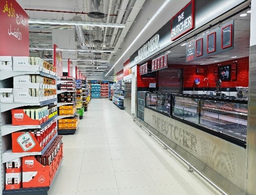 Hypermarket aisle alongside The Butcher counter with red and black branding