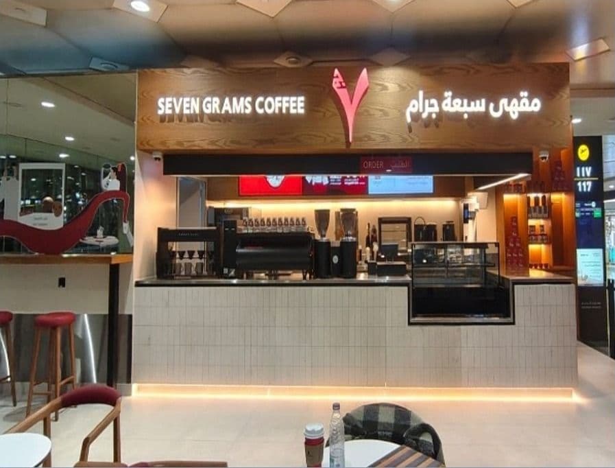 Seven Grams Coffee counter with backlit bilingual signage and an illuminated base